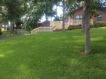 Clean green front yard with trees and house