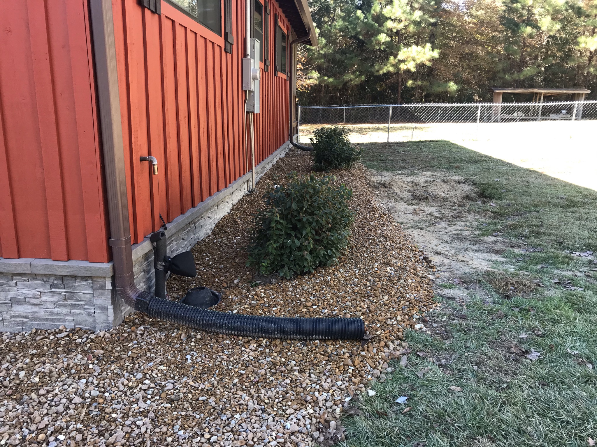 Rock bed with shrubs along red building